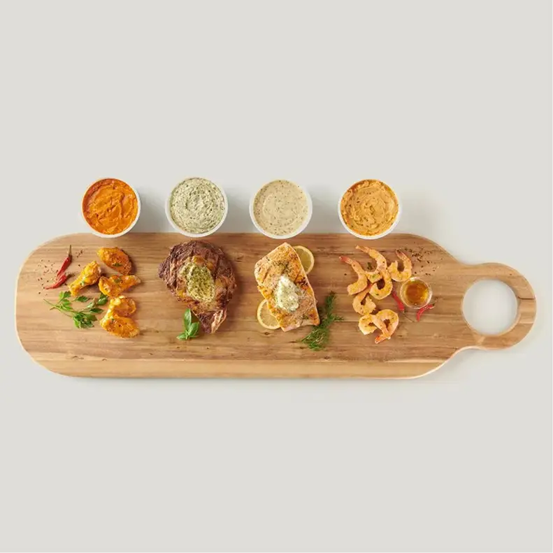 A tasting board of steak, salmon, chicken, and shrimp paired with four flavored butter dipping sauces
