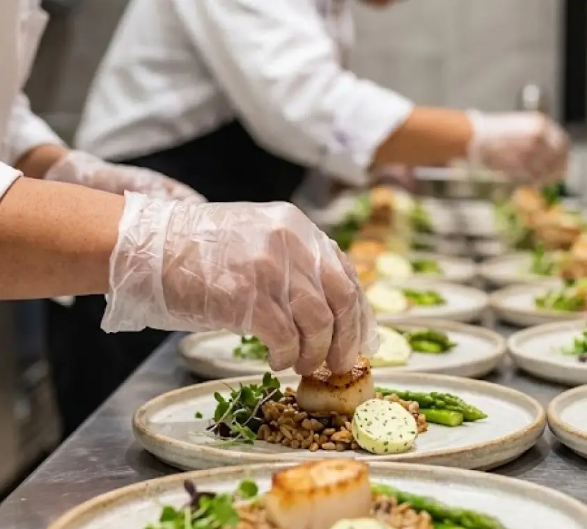 An elegant catered event with white-linen tables, glassware and floral centerpieces