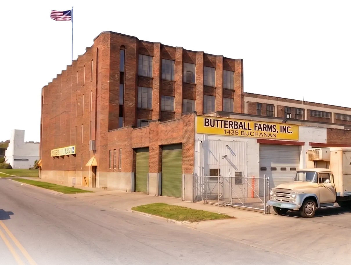 Butterball Farms founder holding a turkey platter in front of the original Grand Rapids factory