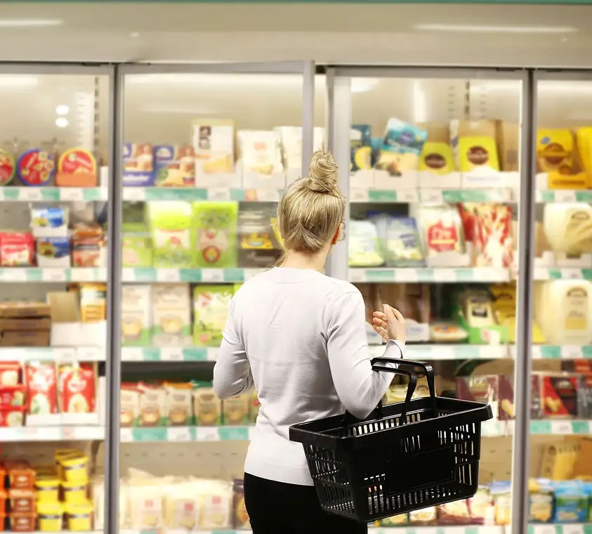 Shopper browsing packaged dairy and butter products in a grocery freezer aisle