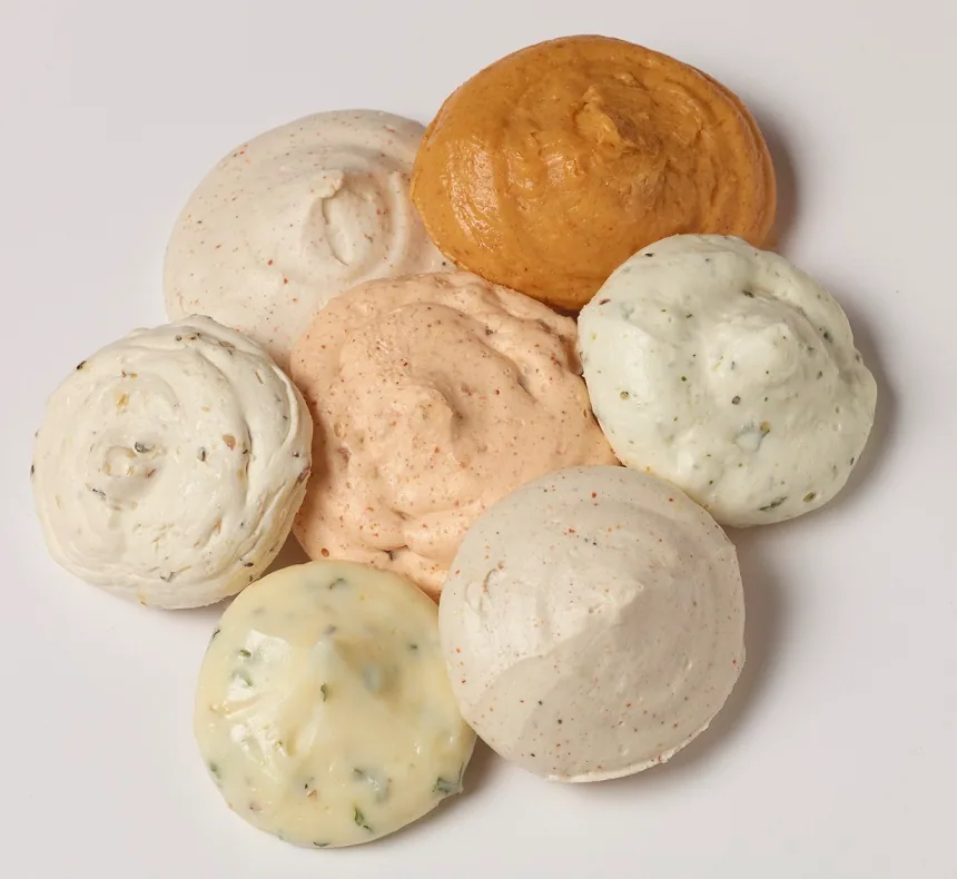 Seven assorted flavored butter dollops arranged in a circular pattern