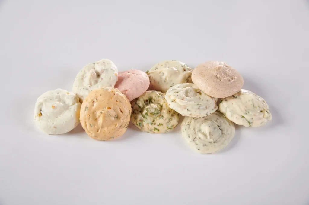 Group of assorted flavored butter dollops in pink, cream and herb-green