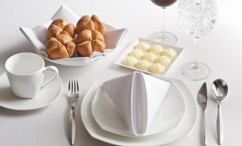Bread rolls, butter dollops and a formal table setting with wine glasses