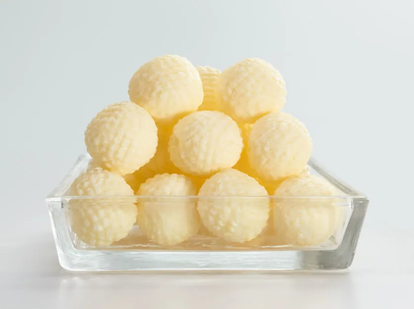 Glass dish of textured butter balls on a plain white background