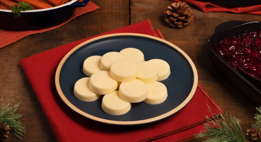 Butter pats on a blue plate with a fall table setting and pinecone