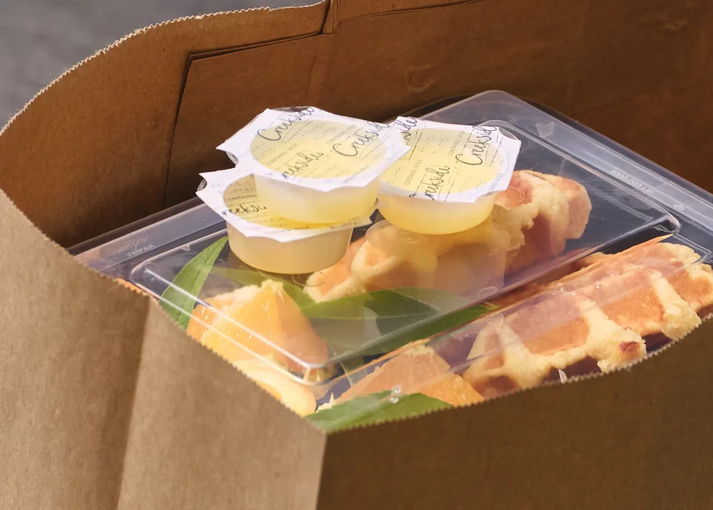Butter portion control cups on a takeout tray inside a paper bag