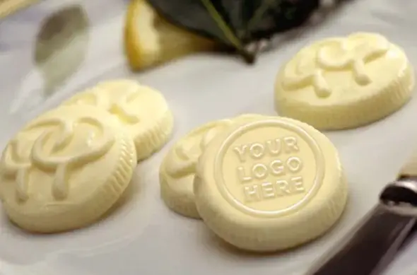 Custom butter pats embossed with a Your Logo Here medallion on a white plate