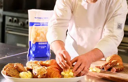 Chef placing butter pieces onto a bread and pastry platter beside a Butterball Farms butter bag