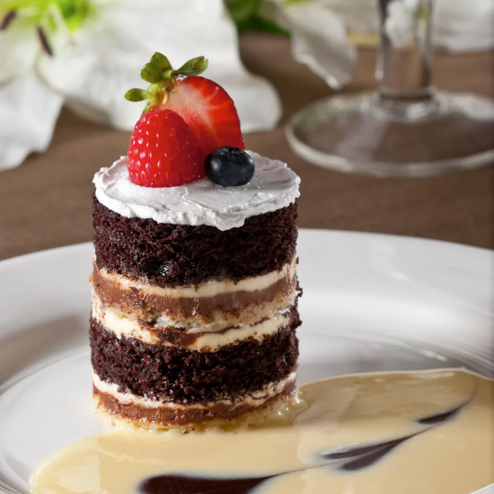 Layered chocolate cake with strawberries and a blueberry on top