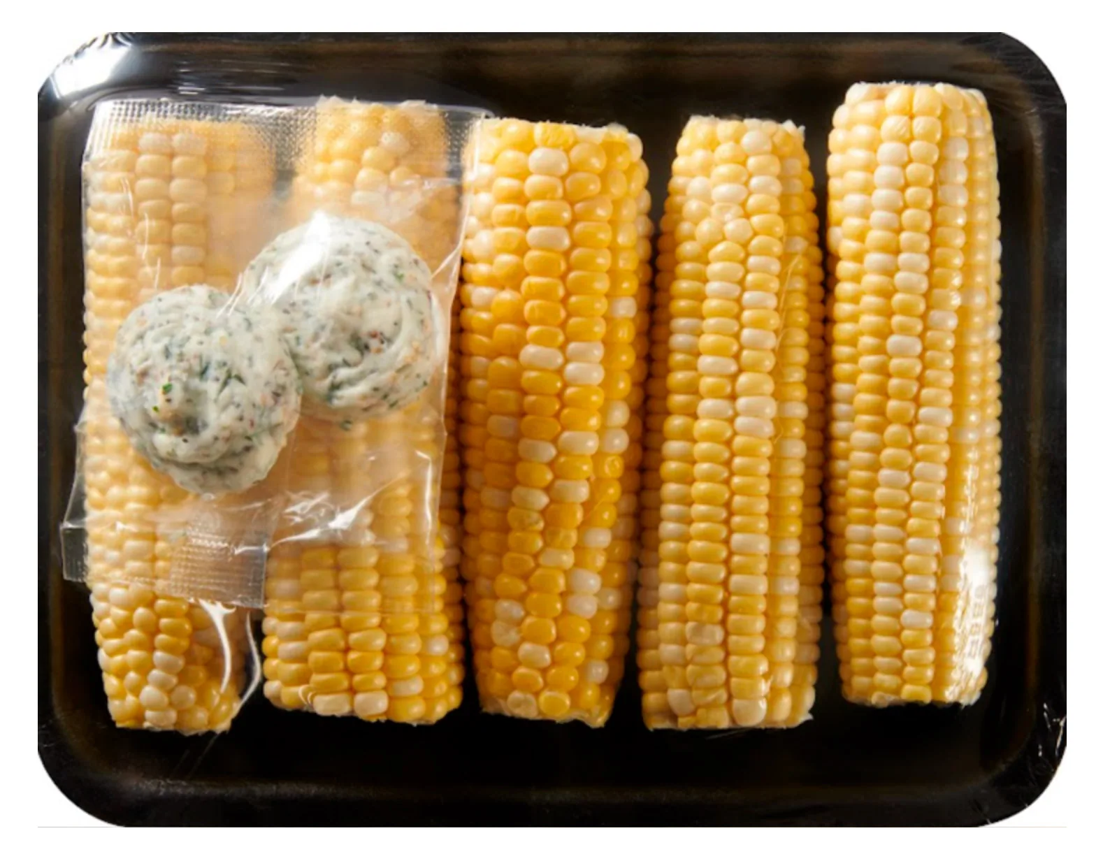 Corn on the cob in a tray with two herb butter dollops
