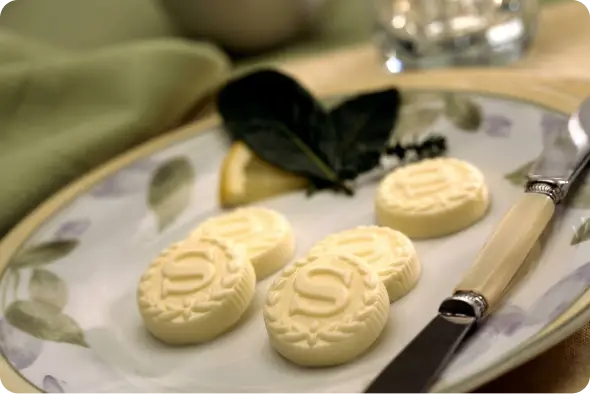 Custom-embossed salted butter portions including a Your Logo Here medallion on a white plate