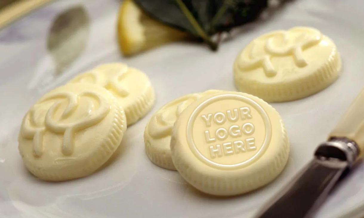 Butter medallions with a knotted pattern, one stamped 'your logo here'