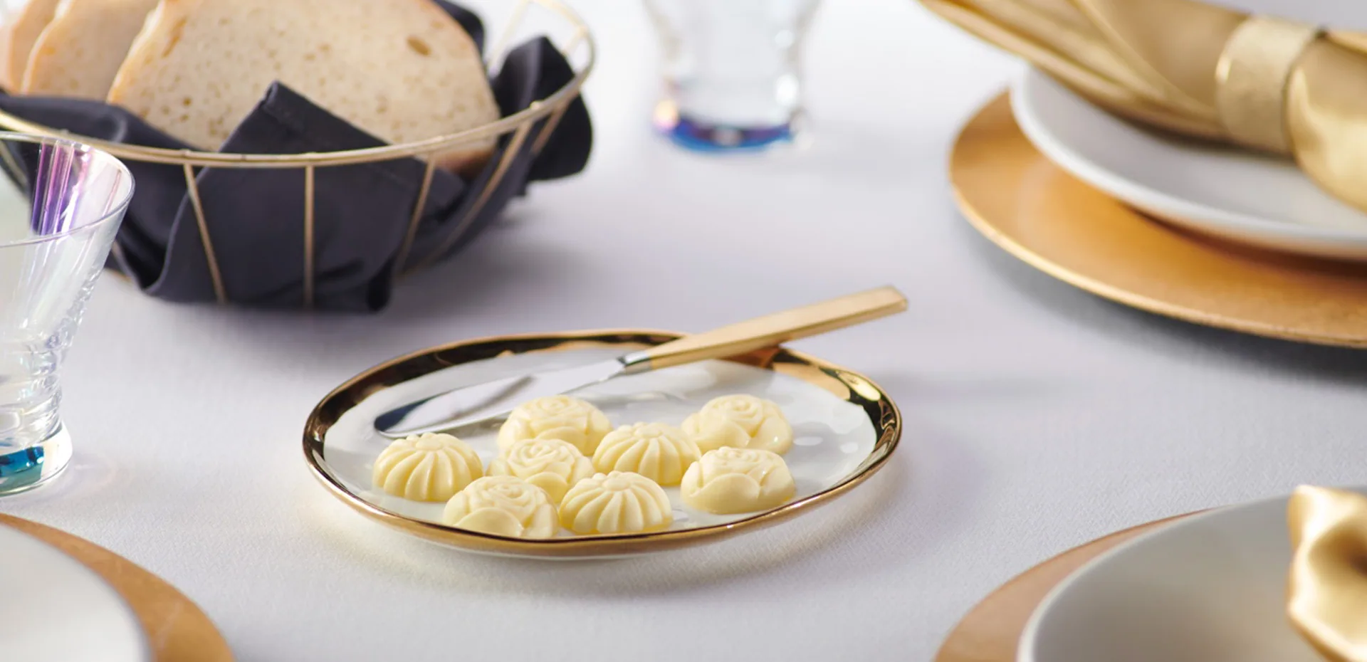 Elegant table setting with bread, wine glasses and a plate of butter rosettes