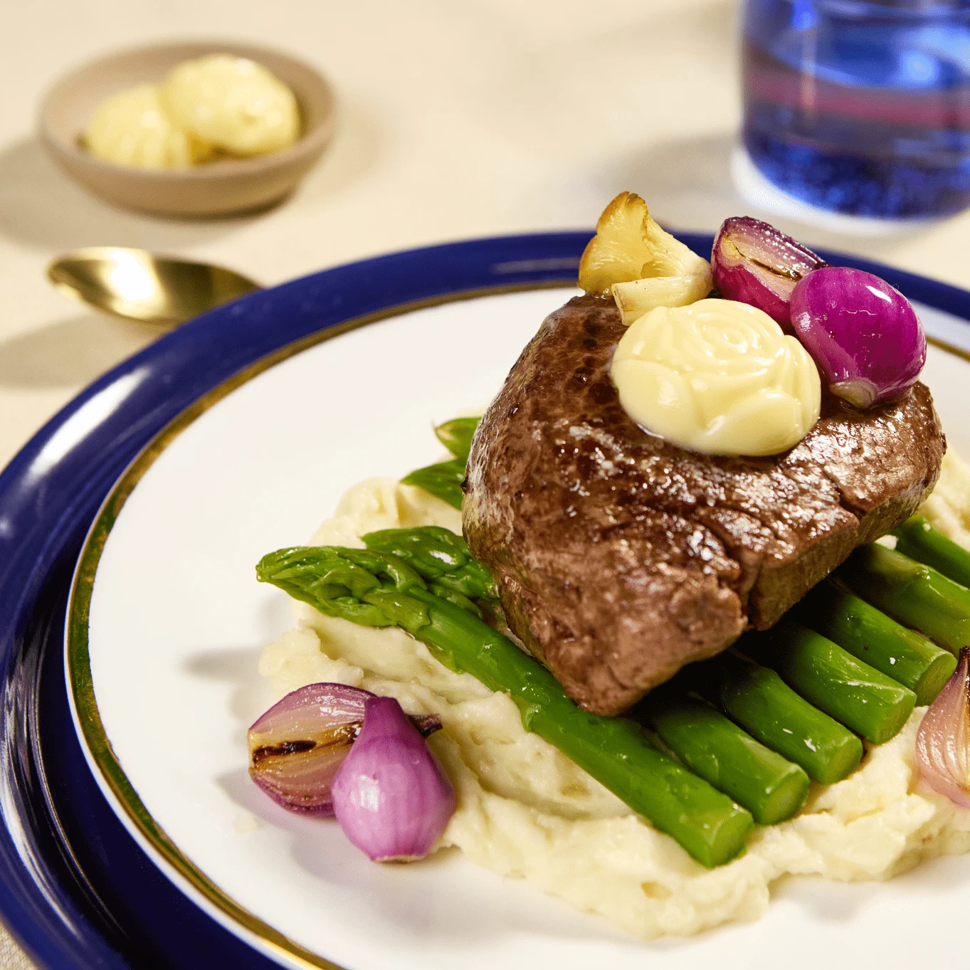 Close-up of filet mignon with a butter rosette, asparagus and roasted shallots