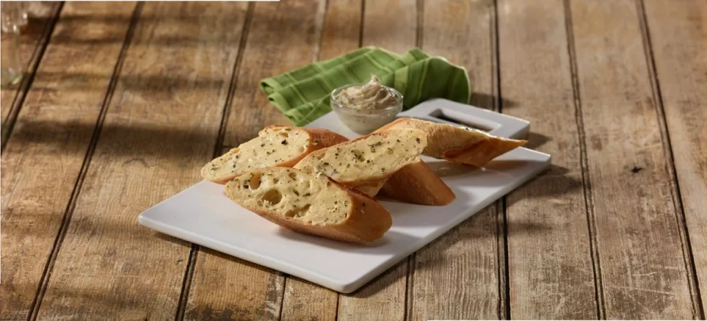 Garlic bread slices on a plate with a bowl of garlic butter spread