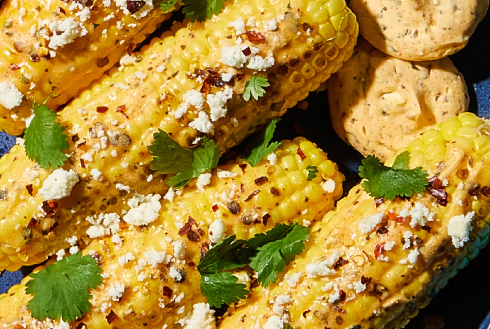 Close-up of grilled corn on the cob with chili flakes and cotija cheese