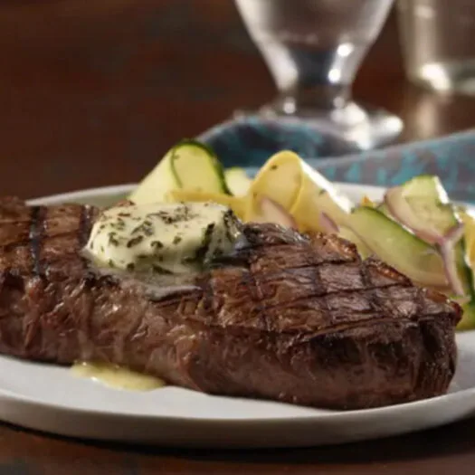 Close-up of a grilled steak with a melting herb butter pat