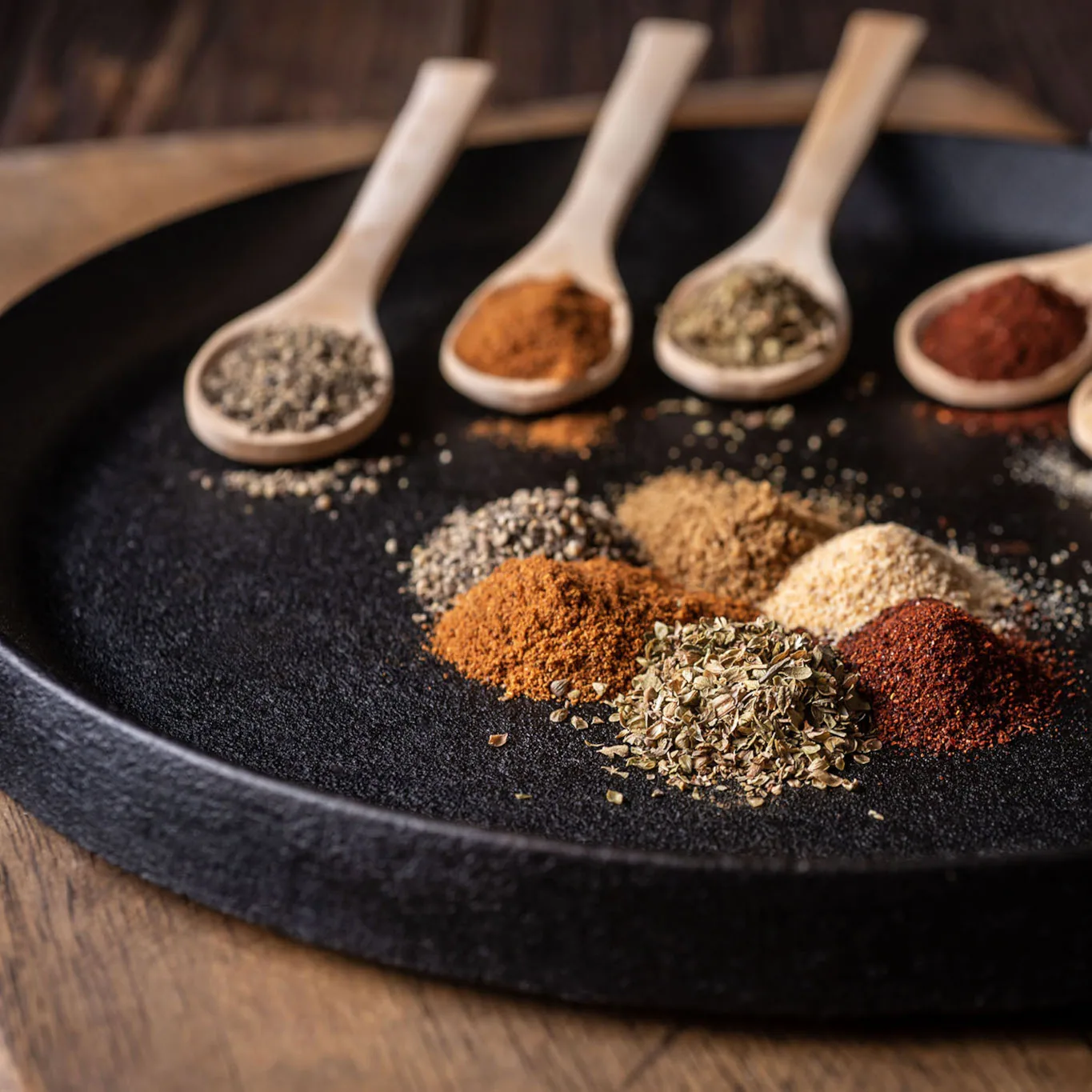 Assorted ground spices arranged on a black platter