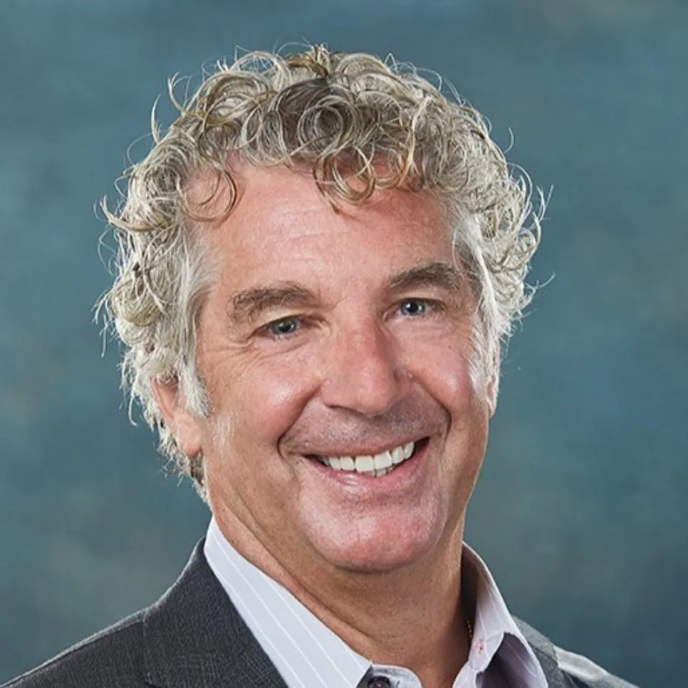 Mark Peters smiling in a headshot wearing a gray suit