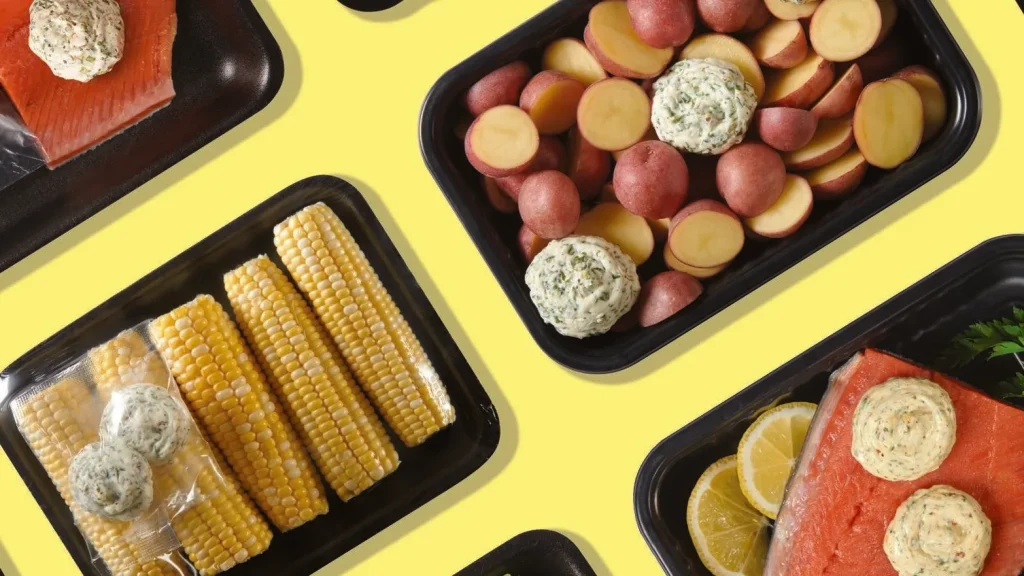 Diagonal overhead view of meal kit trays with salmon and vegetables