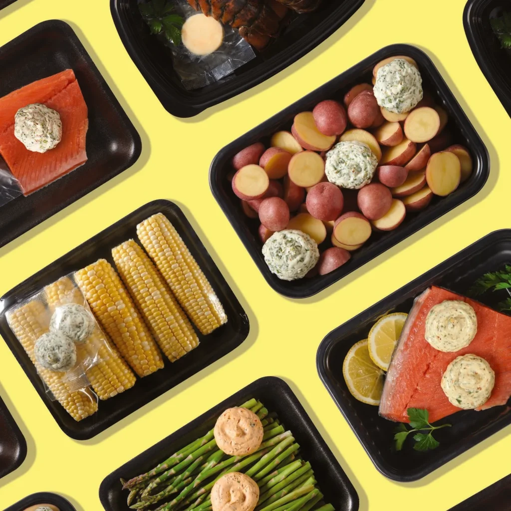 Overhead view of meal kit trays with salmon, potatoes, corn and asparagus