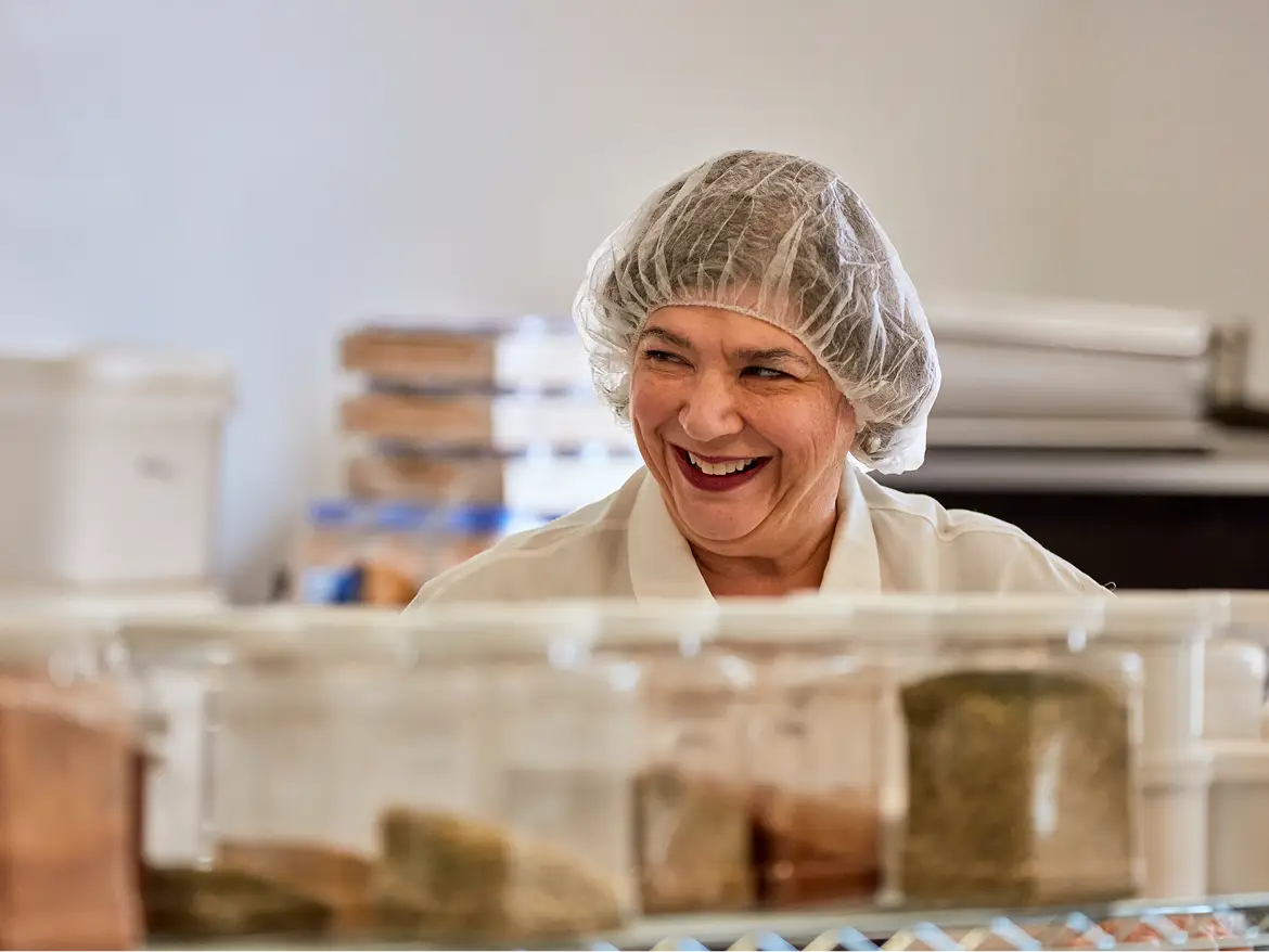 A Butterball Farms team member in a hairnet and gloves stacking packaged product boxes on the production floor