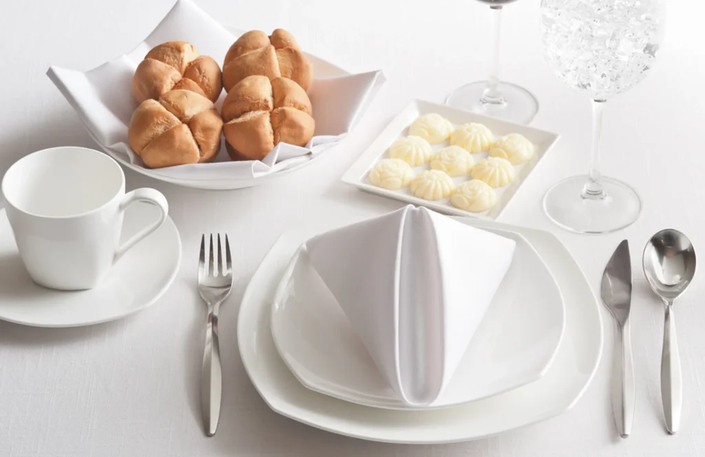 Elegant place setting with bread rolls, nine butter dollops and wine glasses