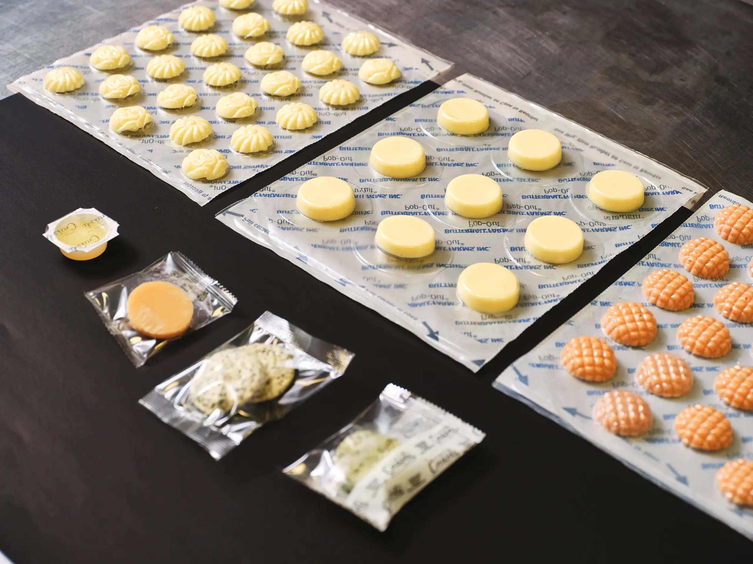 Pop-Out trays of rosettes, medallions and orange lattice butters beside a portion cup and wrapped pats