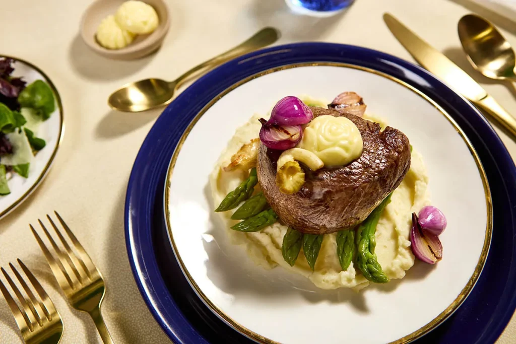 Steak dinner with mashed potatoes, asparagus and a butter rosette on a plate