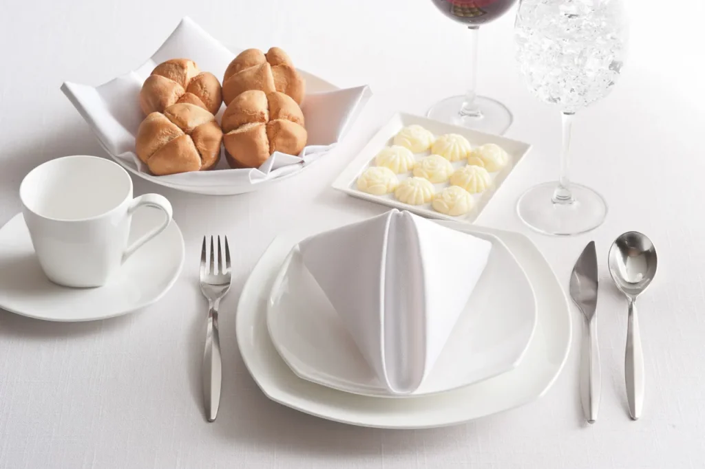 White table setting with bread rolls and a small dish of butter rosettes
