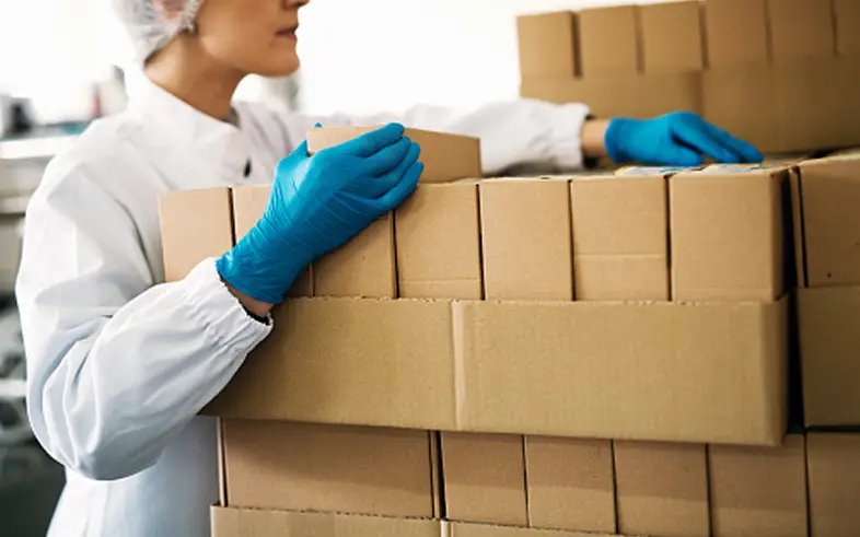 Butterball Farms team member in blue gloves stacking cardboard boxes