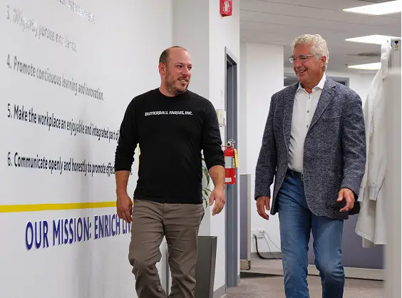 Two Butterball Farms team members walking and talking past a mission statement wall