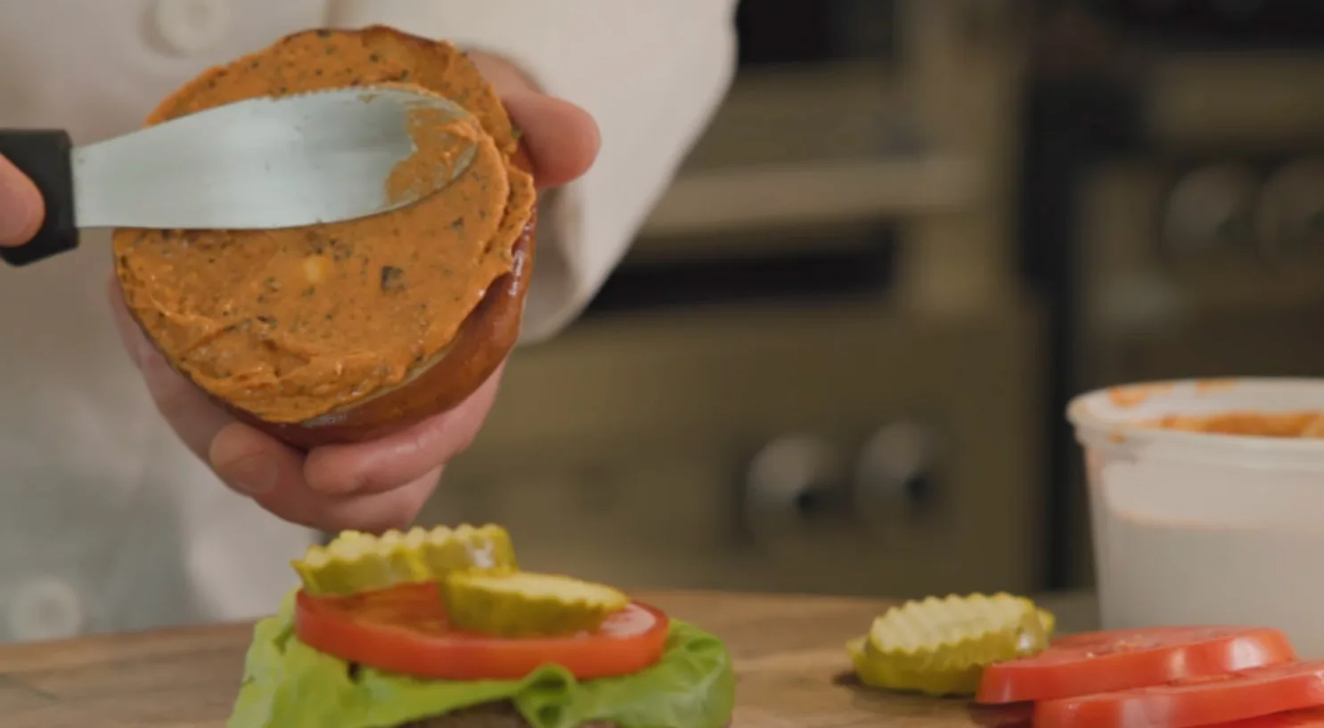 Chef spreading aioli onto a toasted bun